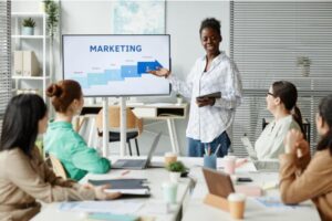 A woman confidently presenting to her colleagues, engaging them with her insights and ideas during a professional meeting.