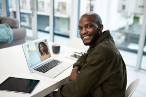 A cheerful man at a desk, focused on his laptop